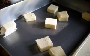 While it is heating, slice the butter into 1 TBS segments and scatter about a 13 x 9 x 2  baking pan.